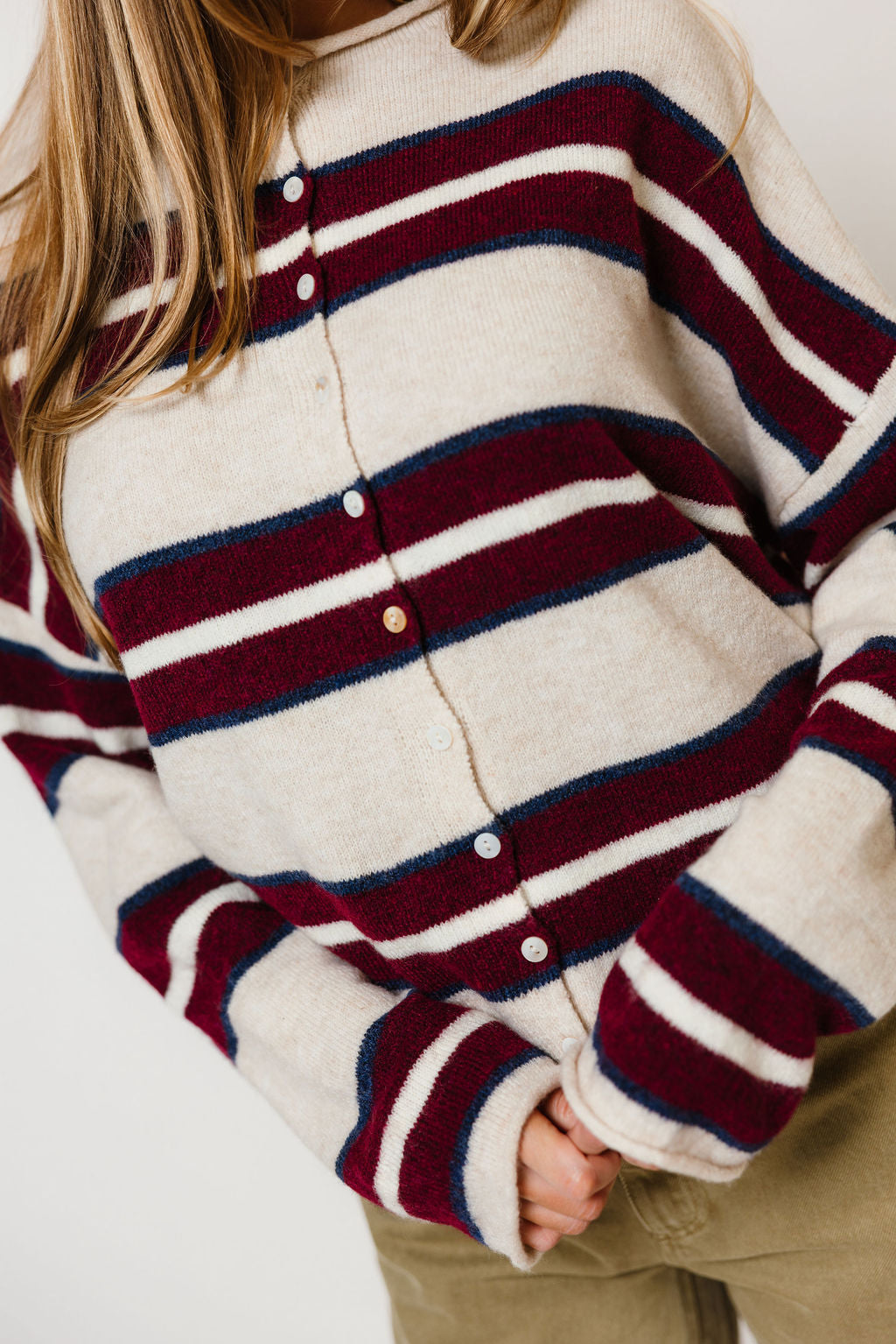 Model in the Piper varsity cardigan in cream with wide burgundy and navy stripes and a button front