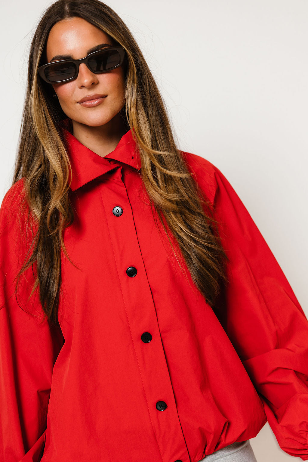 Model in the Savina nylon bubble jacket in bright chili red with a button front and high collar