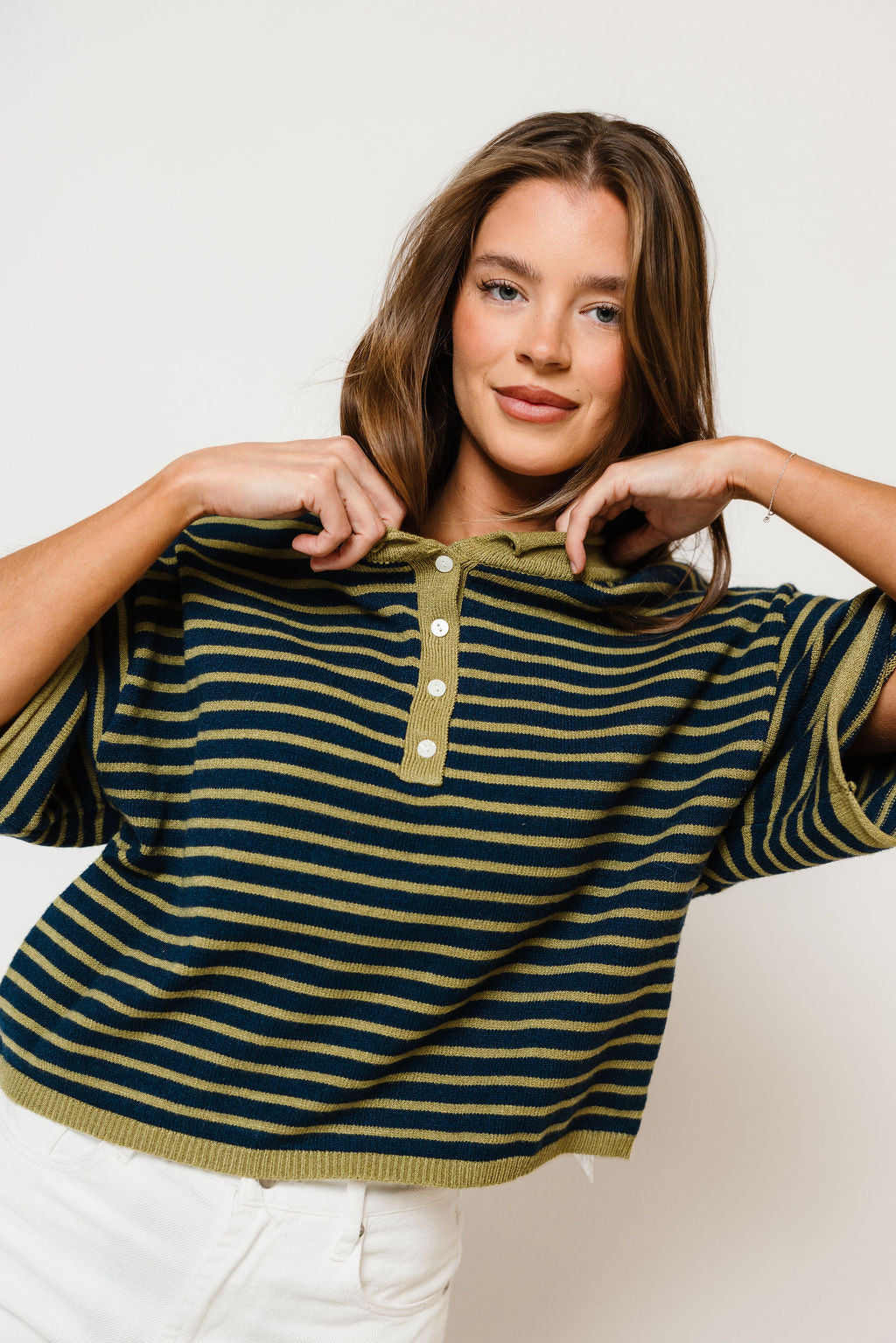 Model in the Jagger striped knit sweater in navy with thin matcha green stripes, a collared half-button neck, dropped shoulders and short sleeves