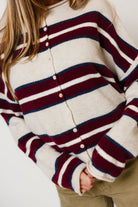 Model in the Piper varsity cardigan in cream with wide burgundy and navy stripes and a button front