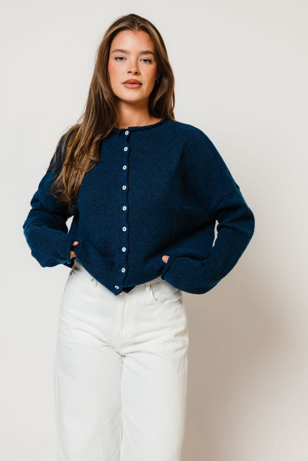 Model in the Piper button-front cardigan in deep navy blue with long sleeves, worn with white jeans