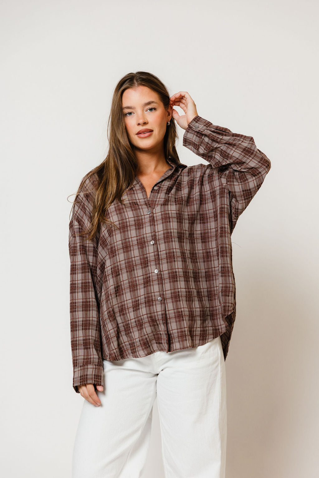 Model in the Cathy oversized button-up shirt in a brown, cream and blue plaid, worn with white pants