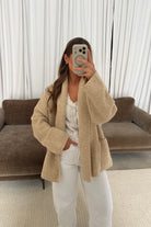 Mirror selfie of a model in the Annabelle relaxed shawl collar open front cardigan in oatmeal beige, worn with white pants