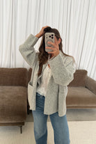 Mirror selfie of a model in the Annabelle relaxed shawl collar open front cardigan in pale birch grey, worn with light jeans